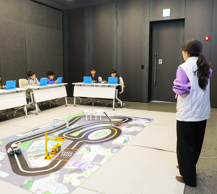  남성 운전자와 드라이빙 체험을 하는 3명의 남자 아이의 모습